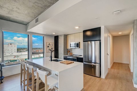 a kitchen with a large island and a stainless steel refrigerator
