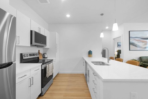 A modern kitchen with white cabinets and stainless steel appliances.