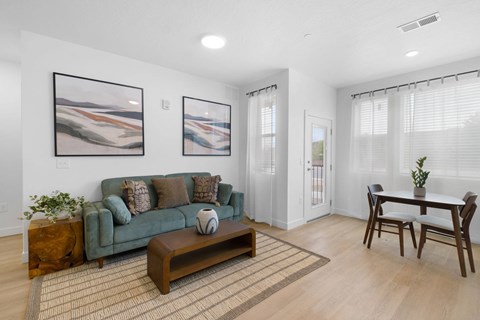 A living room with a green couch, a coffee table, and two framed pictures on the wall.