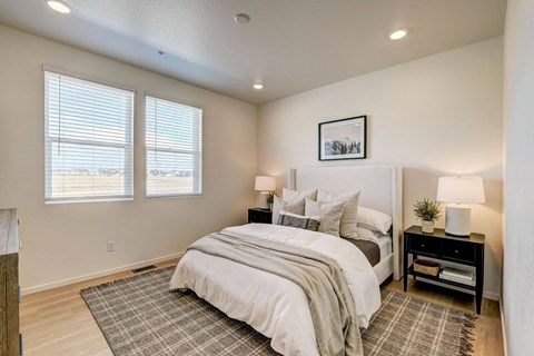 A bedroom with a large bed and a window with blinds.