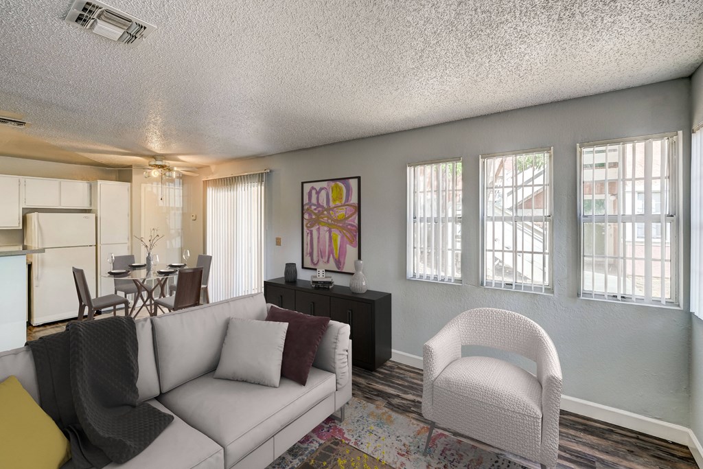 a living room with a couch and a chair and a kitchen with a table