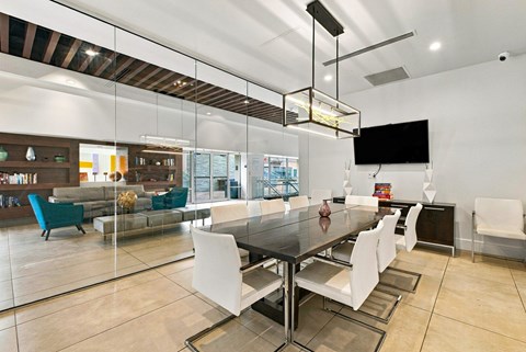 A modern dining room with a glass table and white chairs.