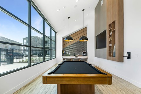 A pool table in a room with a view of the outside.