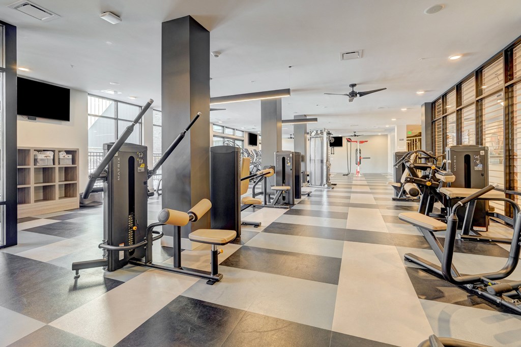 a gym with cardio equipment and a flat screen tv