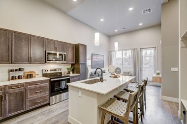 One bedroom model kitchen with island and wood-style flooring and view to living room