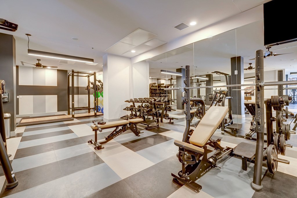 a spacious fitness room with weights and cardio equipment