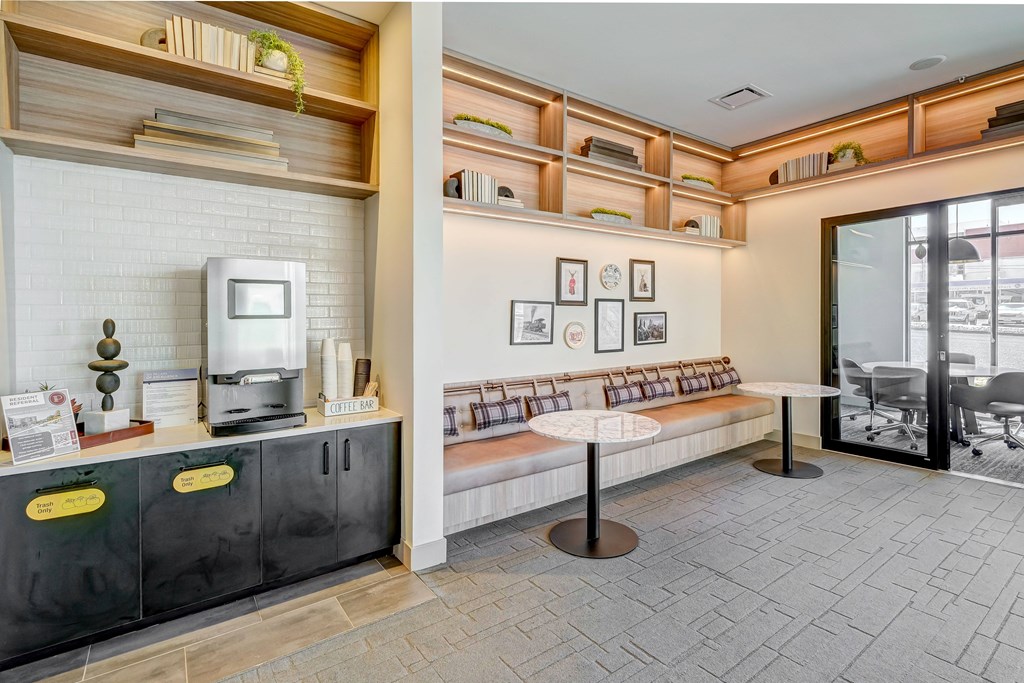 a room with a coffee machine and a table with a book shelf in the background