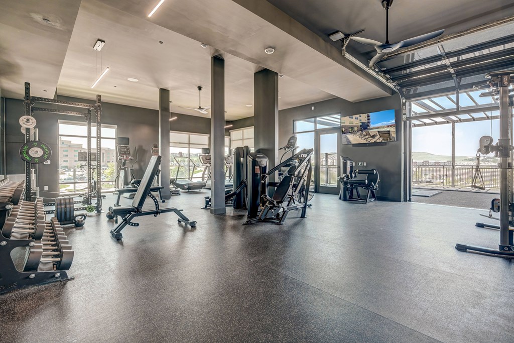 A spacious gym with various exercise equipment and a large window.