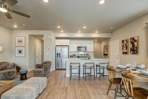 A modern open plan living and kitchen area with a dining table set for two.