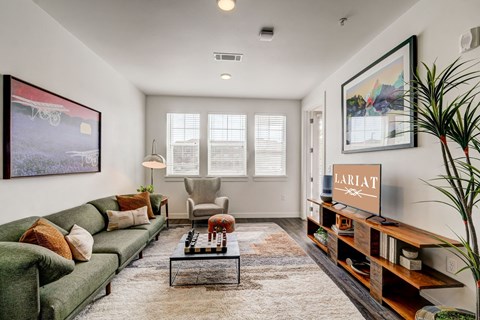 A living room with a green couch, a coffee table, and a painting on the wall.