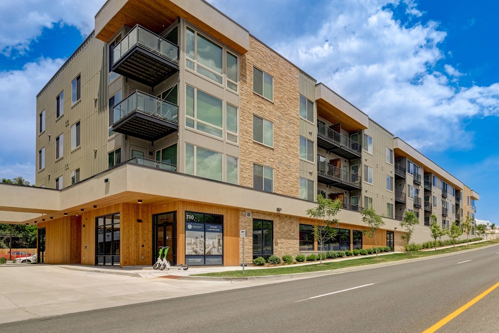 an apartment building with a street in front of it and a blue sky in the background