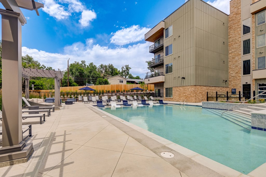 a swimming pool with lounge chairs and umbrellas next to a building