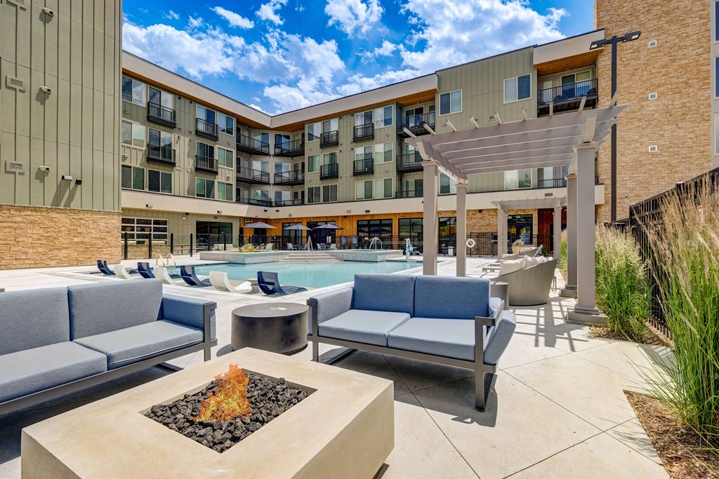 a patio with couches and chairs and a fire pit in front of a building