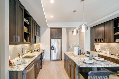 A modern kitchen with dark wood cabinets and a marble countertop.