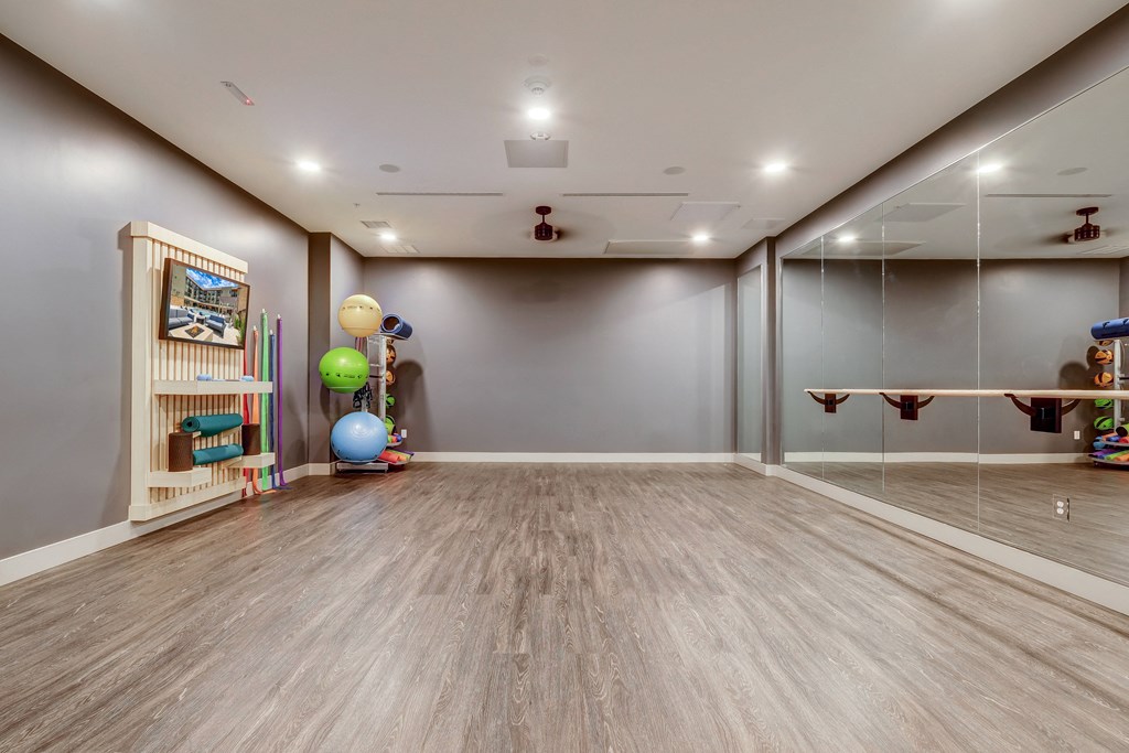 a workout room with a mirrored wall and wooden bookshelf