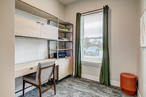 A room with a desk, chair, and shelves.