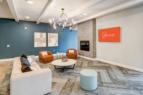 A living room with a white couch, orange chairs, and a chandelier.