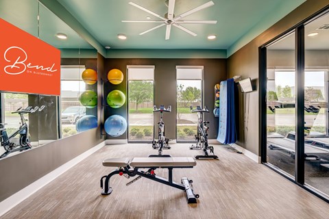 A gym with a row of exercise bikes and a bench with a leg press machine.