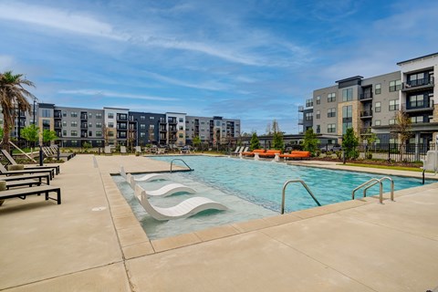 A swimming pool with a slide and a bench in front of apartment buildings.