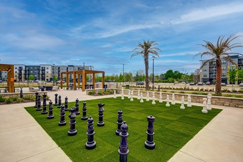 A chess set is set up on a green lawn.
