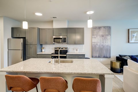 A modern kitchen with a large island and chairs.