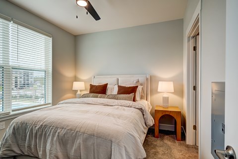 A bedroom with a large bed and a window with blinds.