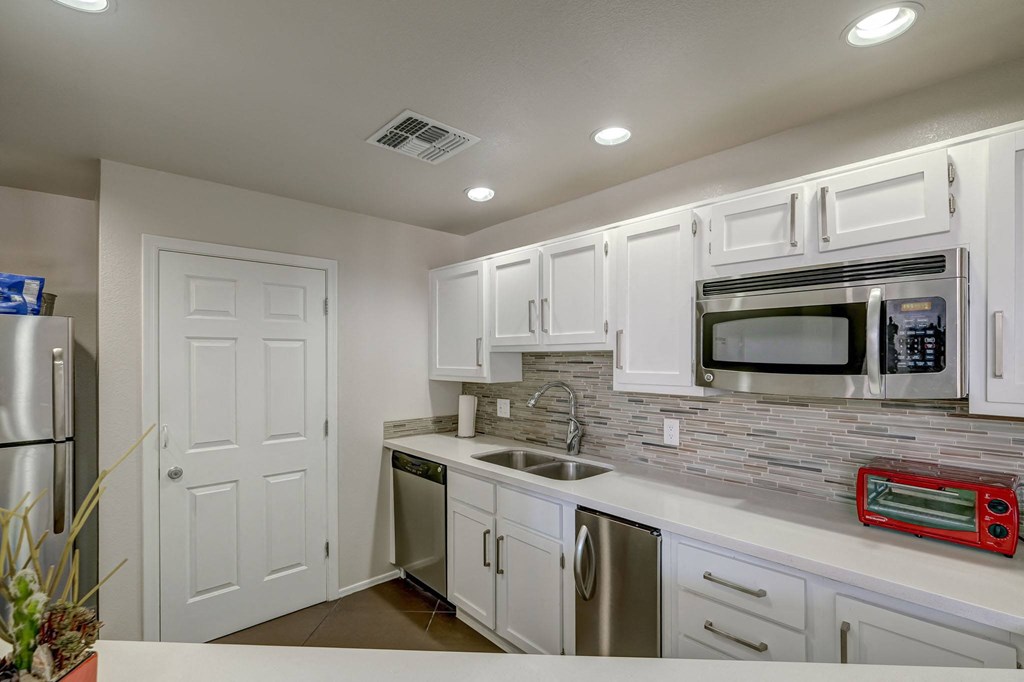 a white kitchen with stainless steel appliances and white cabinets