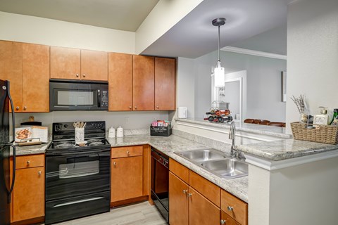 A kitchen with a black oven and wooden cabinets.