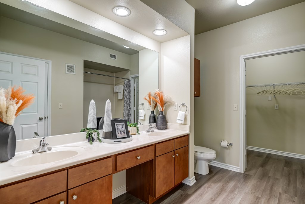 A bathroom with a vanity, sink, mirror, and toilet.