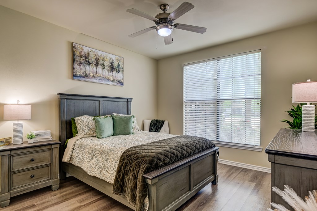 A bedroom with a bed, nightstand, and a painting on the wall.