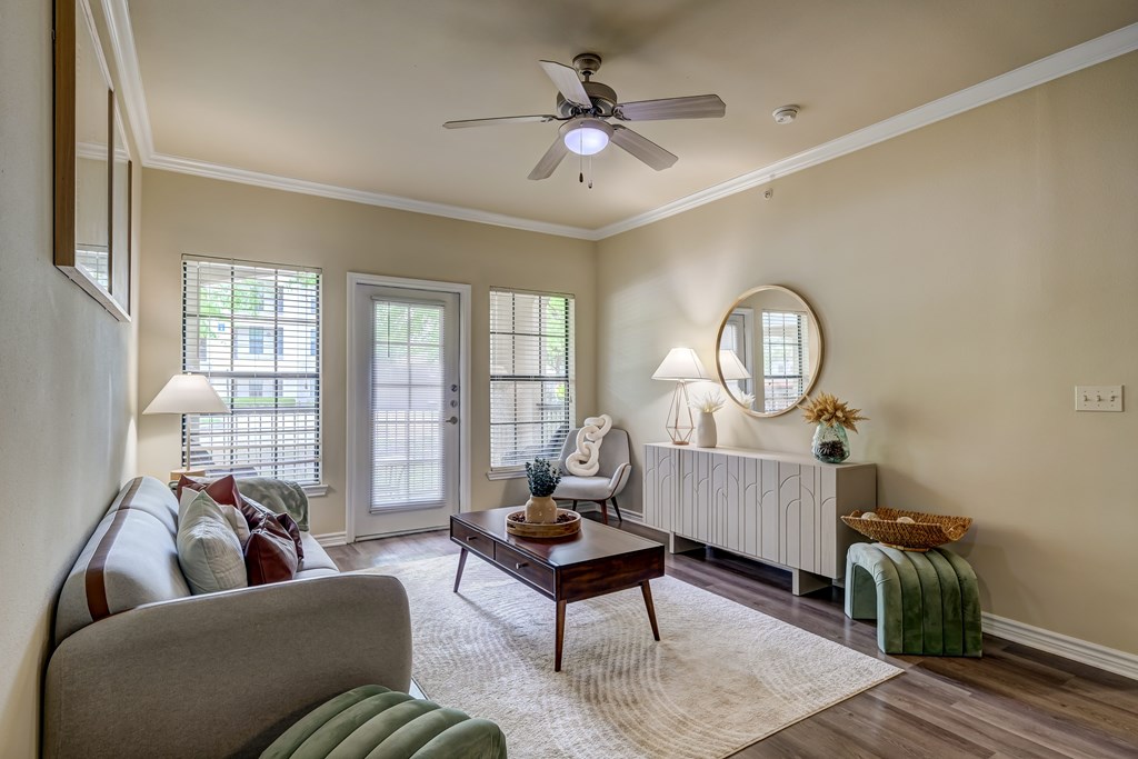 A living room with a grey couch, a wooden coffee table, a white radiator, and a ceiling fan.