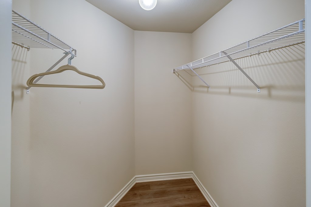 A walk in closet with a hanger and shelves.