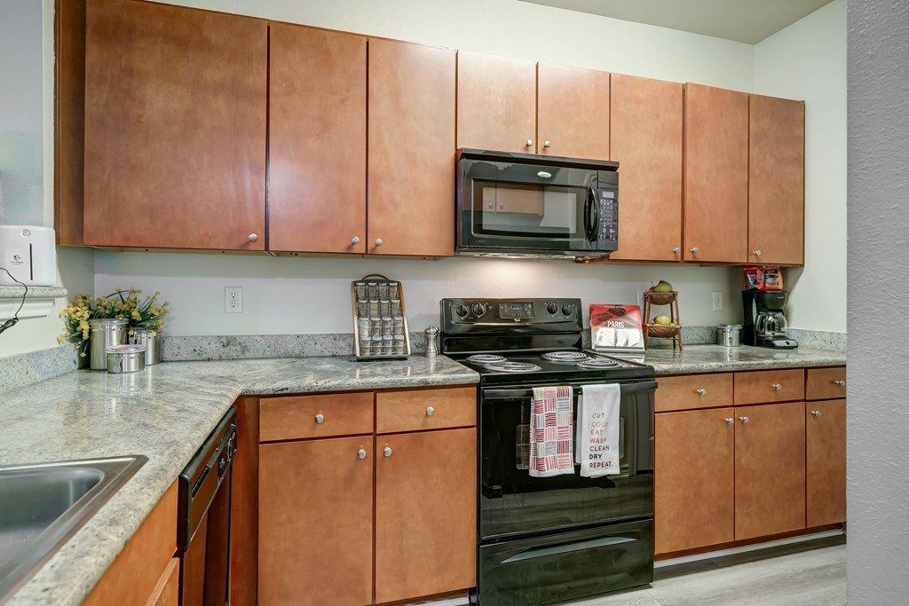 A kitchen with brown cabinets and a black stove top oven.