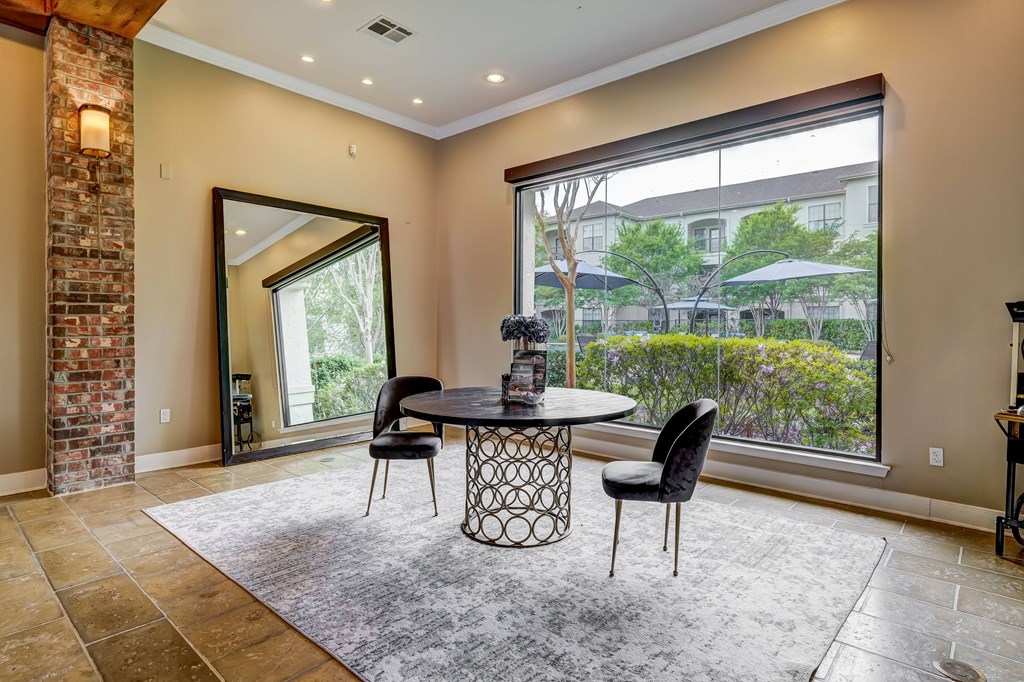 A dining room with a table and chairs and a large window.