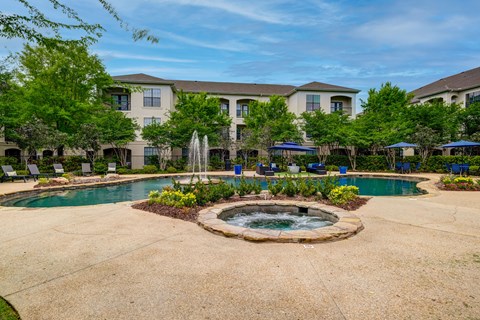 A large building with a pool and fountain in front.