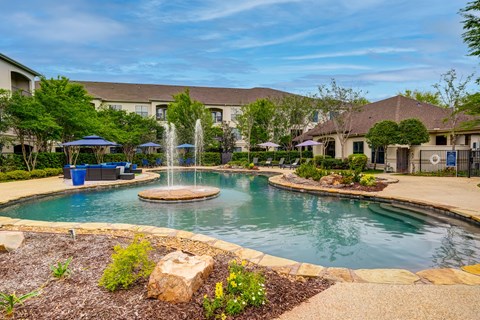 A beautiful outdoor swimming pool with a fountain in the middle of it.