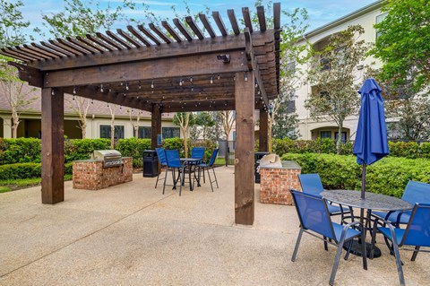 A patio with a table and chairs under a wooden pergola.