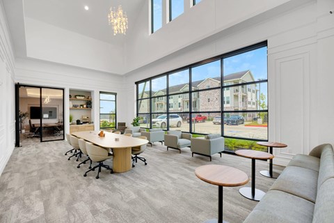 A spacious room with a long table and chairs, large windows, and a view of the outside.