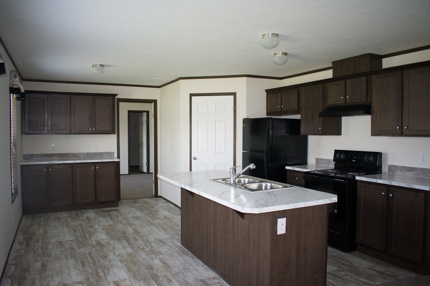 A kitchen with brown cabinets and a black refrigerator.