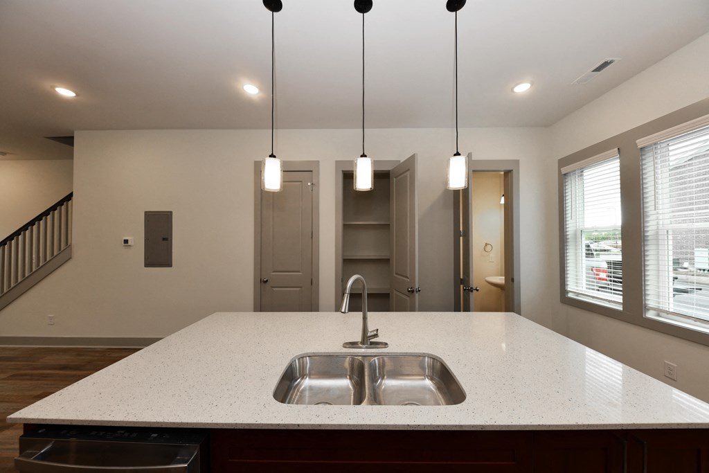 A modern kitchen with a white countertop and a double sink.