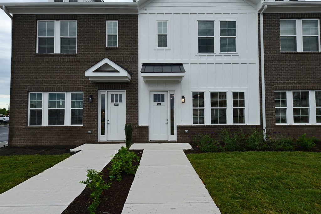 A white and brown building with a walkway in front.