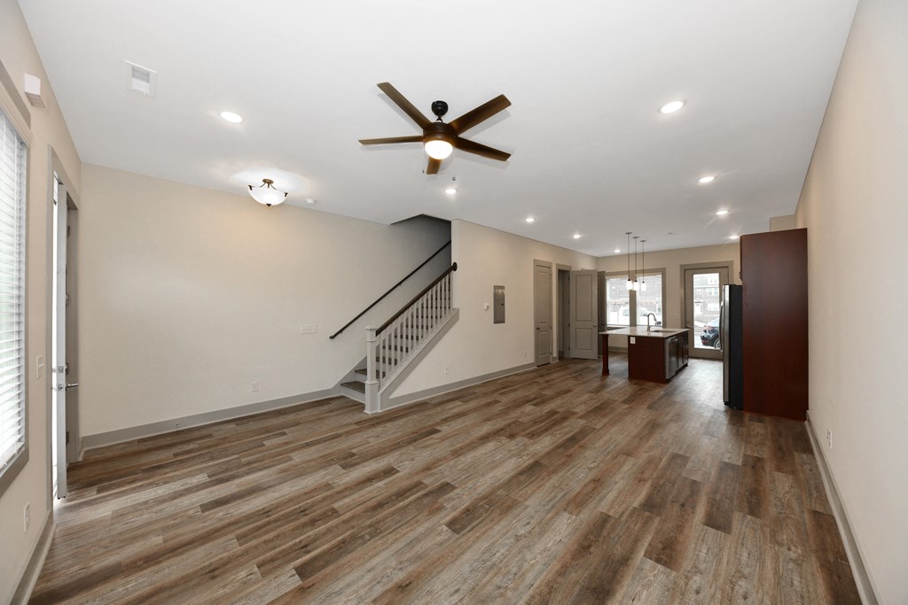 A spacious room with a wooden floor and a ceiling fan.