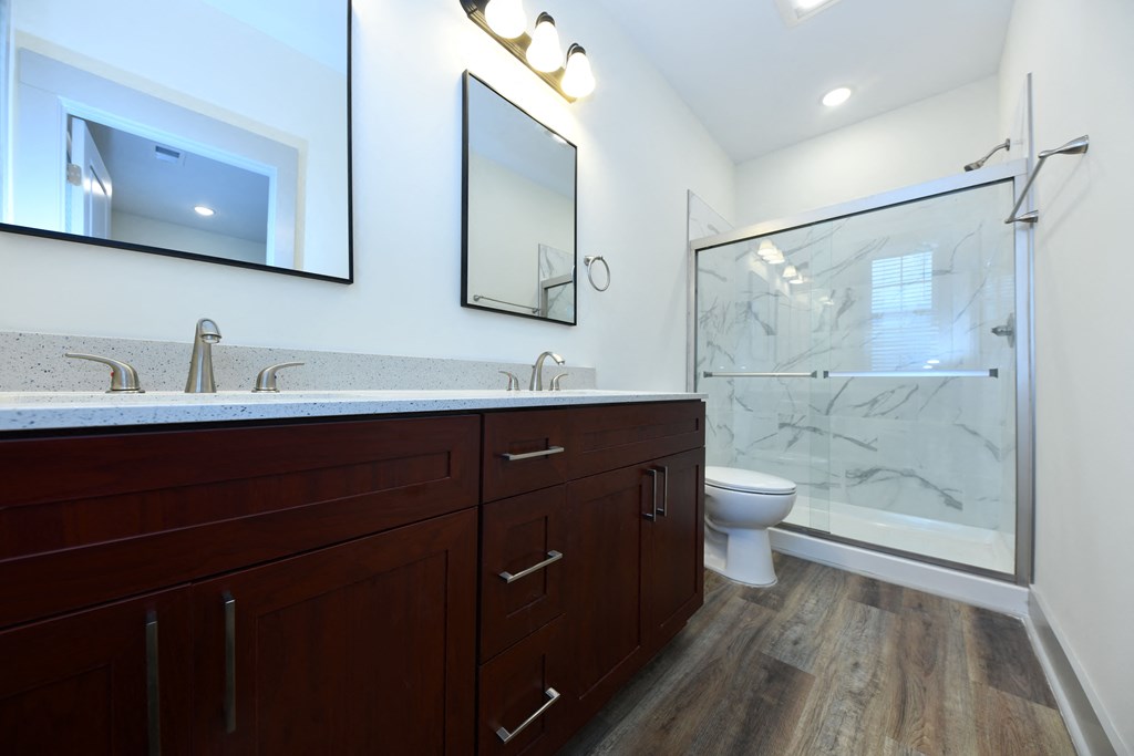 A modern bathroom with a marble countertop and wooden flooring.