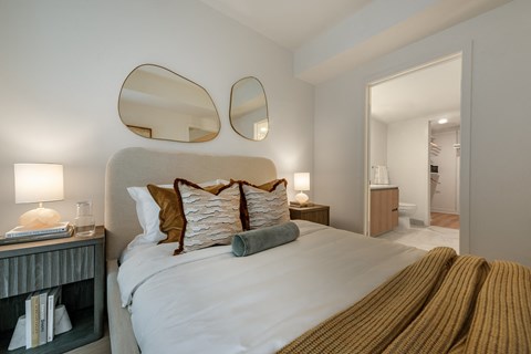 A bedroom with a large bed and two mirrors above it.