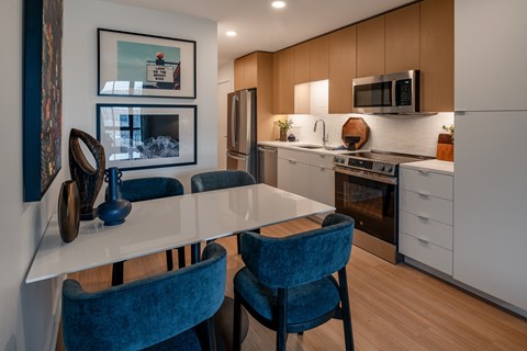 A modern kitchen with a white table and blue chairs.