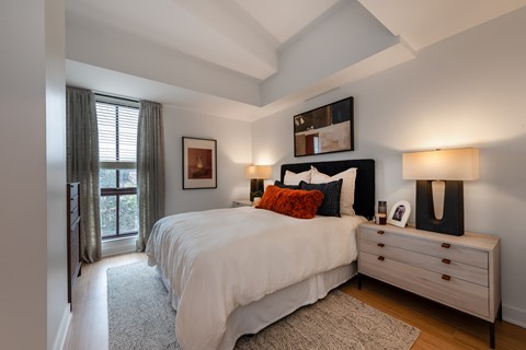 A bedroom with a large bed, a dresser, and a window with curtains.