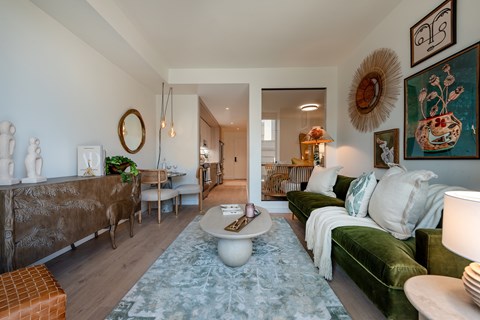 A living room with a green velvet couch and a white coffee table.