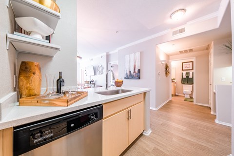 a kitchen with a sink and a dishwasher and a hallway with a bathroom