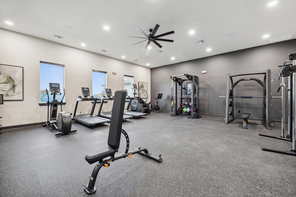 A spacious gym with a variety of equipment including treadmills, elliptical machines, and weight machines.