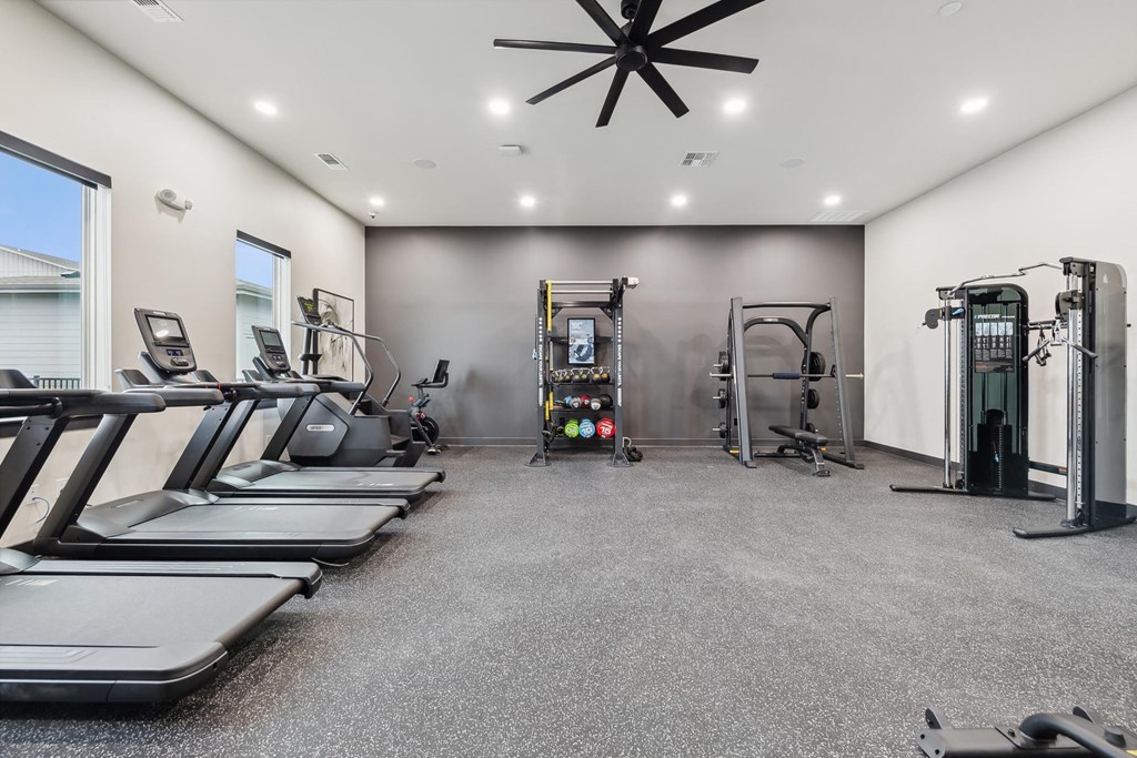 A spacious gym with treadmills, elliptical machines, and a weight rack.